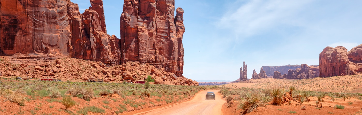 Desert road with car ahead in the United States.