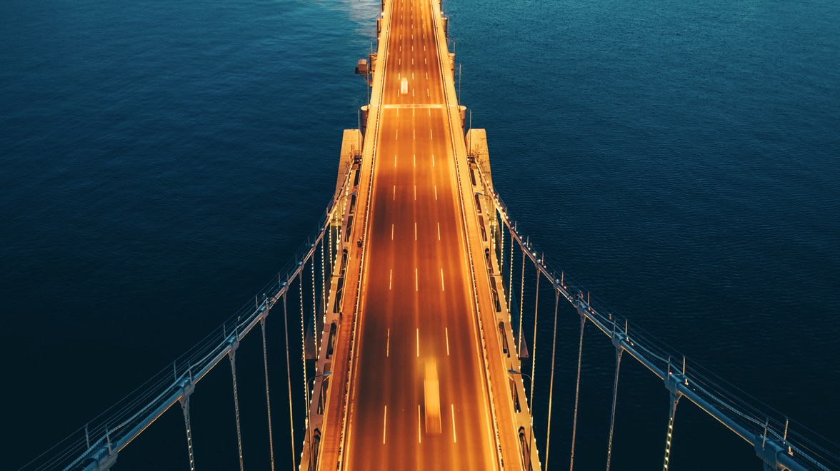 Arial view of illuminated bridge at night over body of water.