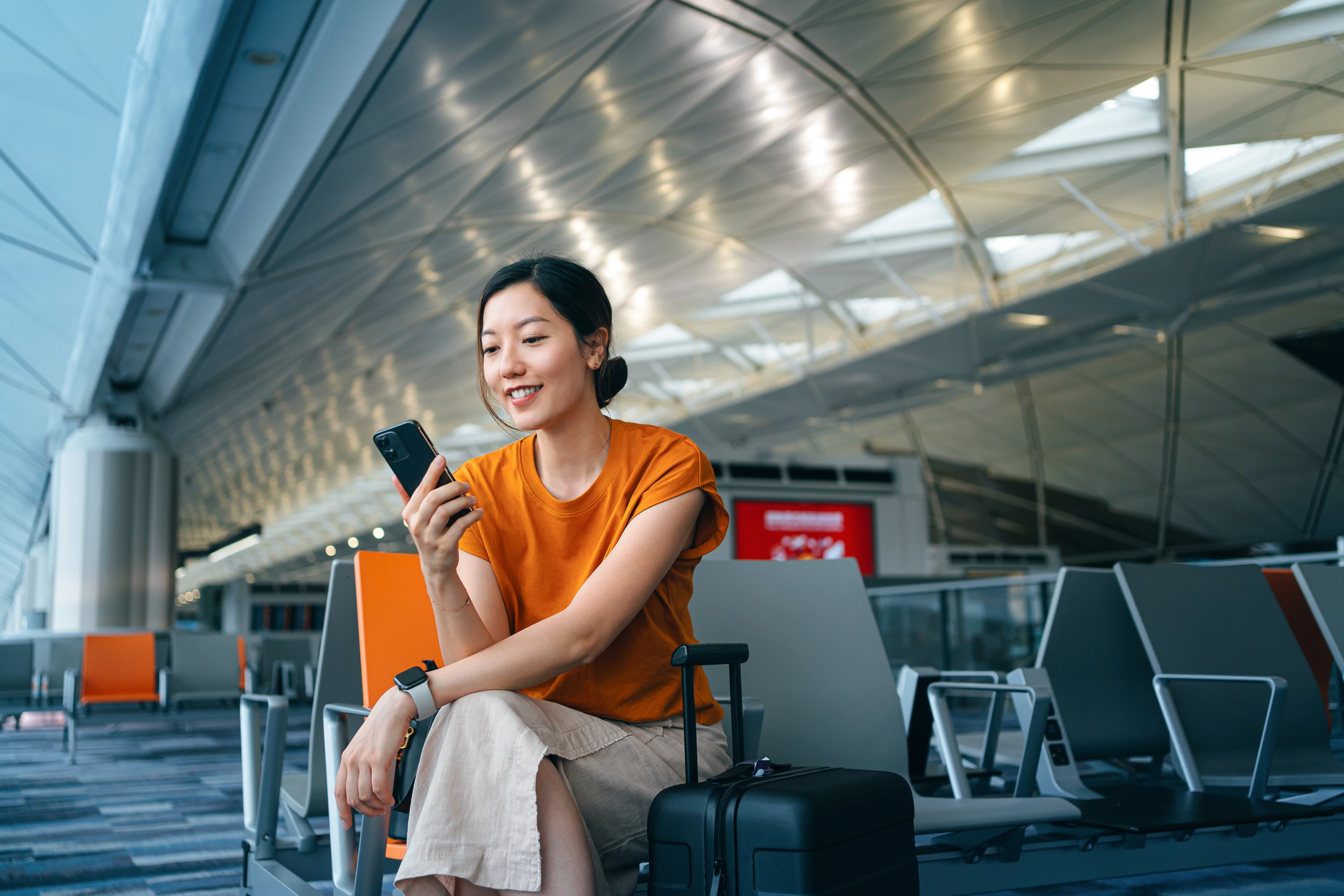 Woman seated smiling at phone.