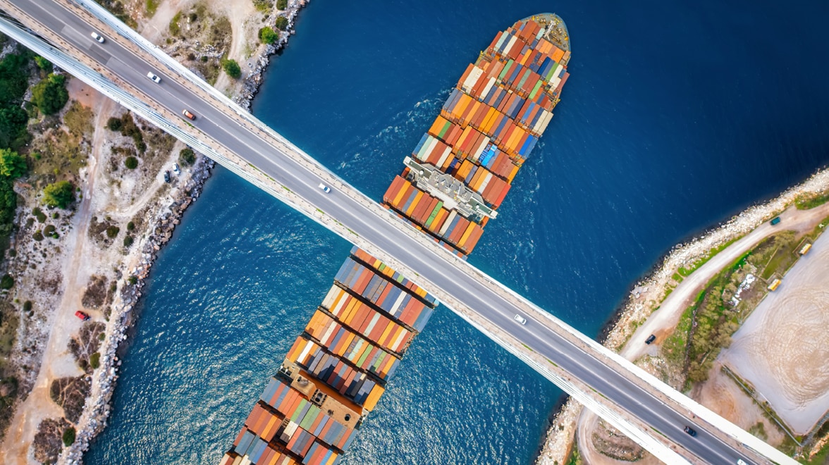 Arial view of car road bridge over water and large boat.