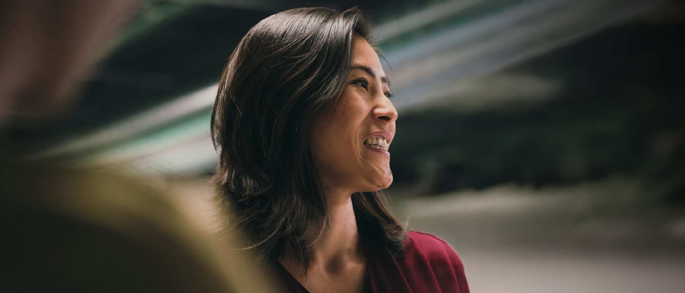 Person in a red jacket looking to the side in an office setting.
